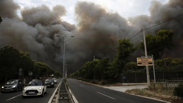 Smoke rise over an avenue during a forest fire in Neo Voutsa, a northeast suburb of Athens, Greece, 23 July 2018.