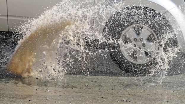 Carro pasando por un charco.