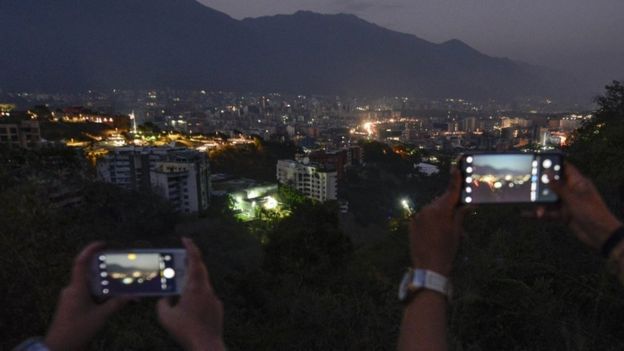 Personas tomando fotos a Caracas a oscuras con sus teléfonos.