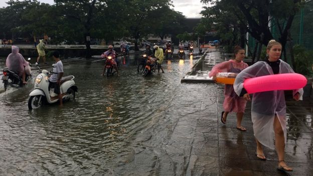 Tourists use rubber rings to cross a flooded road on Ko Samui, Thailand, 5 January 2017