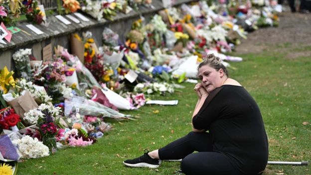 سيدة نيوزيلندية تجلس حزينة أمام آلاف باقات الزهور التي وضعت أمام مدخل المستشفى في مدينة كرايستت تشيرتش