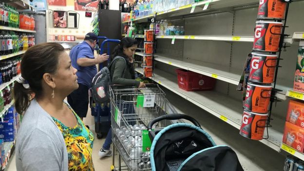 Varias personas buscan víveres en un supermercado con estantes vacíos en Miami, Florida.