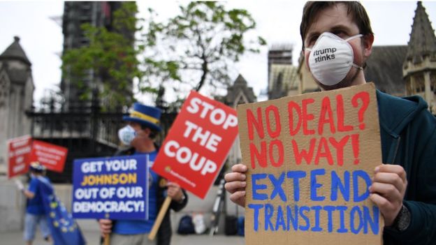 Protesters hold signs calling for an extension to the transition