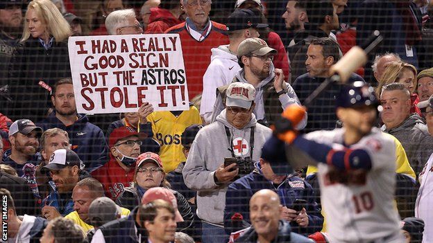 A Boston Red Sox fan holds up a sign referencing the Houston Astros sign-stealing scandal