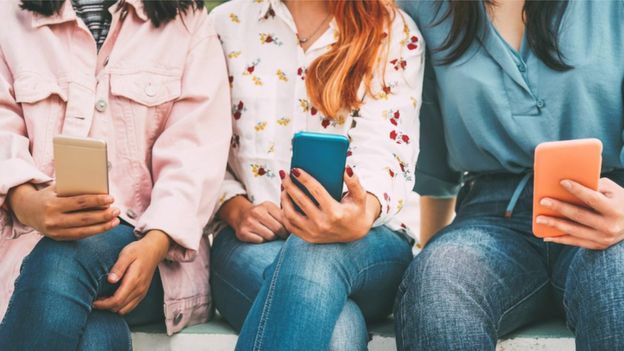 Amigos usando smartphones em público