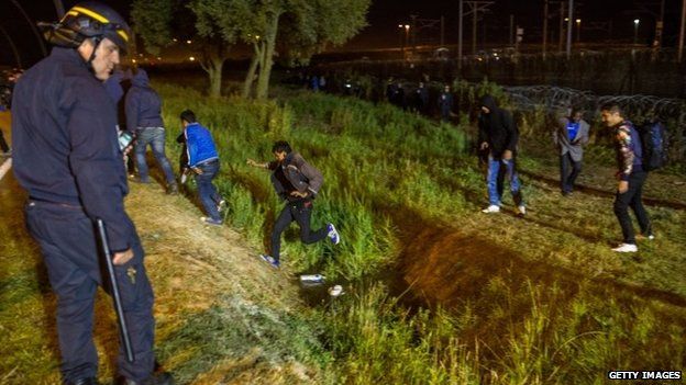 Police with migrants near the Eurotunnel terminal in Coquelles
