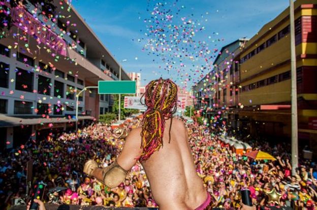 Homem joga confete em multidão no Carnaval