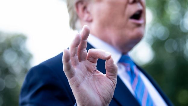Foto de Trump foca em sua mão, sinalizando gesto enquanto fala