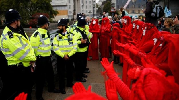 "The Red Brigade" activists gesture in front of police officers in London