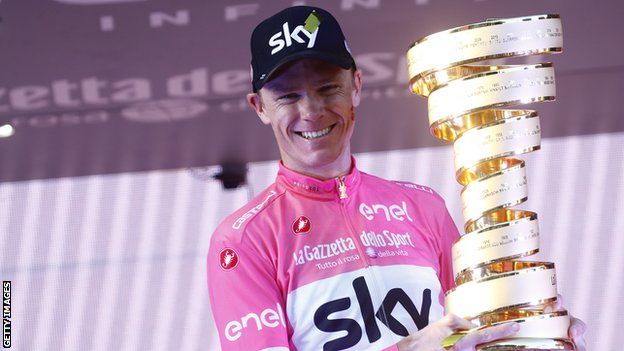Team Sky rider Chris Froome smiles while wearing the pink jersey and holding up the 2018 Giro d'Italia trophy