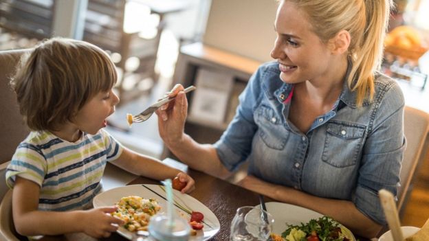 Madre dándole de comer a su niño.