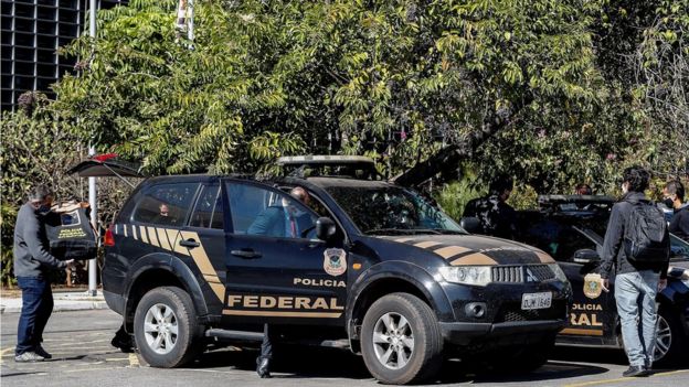 Carro da pol&iacute;cia federal e agentes