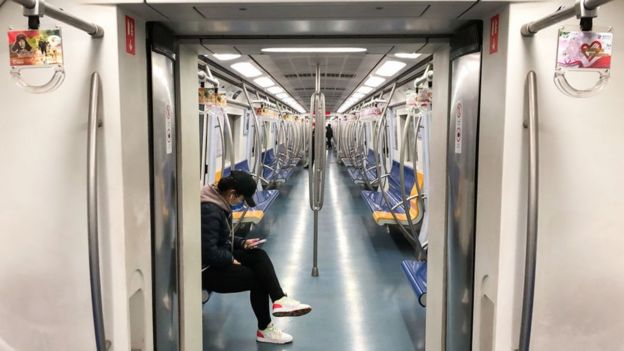 A man wearing face mask sits in a train carriage