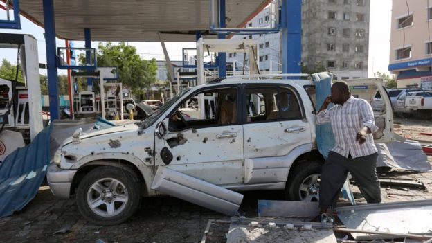 A man looks at the wreckage of his car destroyed at a petrol station during an in Mogadishu on 26 June