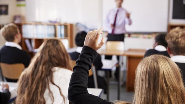 los niños en la escuela levantan la mano