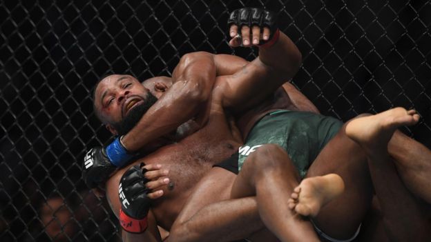 Kamaru Usman (blue gloves) and Tyron Woodley (red gloves)