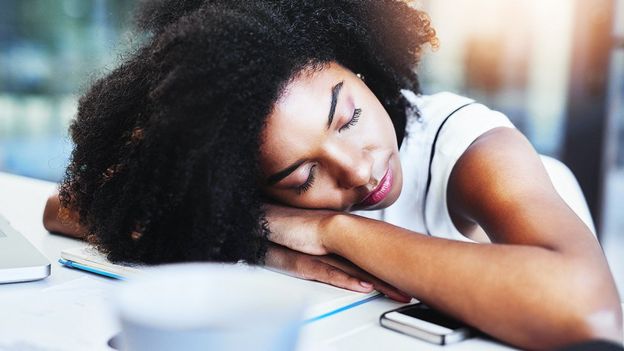 Mujer echando una siesta en la mesa.