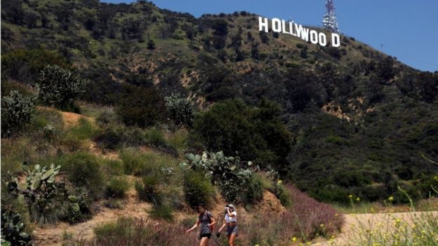 People hike beneath the Hollywood sign after a partial reopening of Los Angeles hiking trails during the outbreak of the coronavirus disease