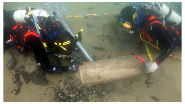 Divers work to recover a cannon from the sea bed