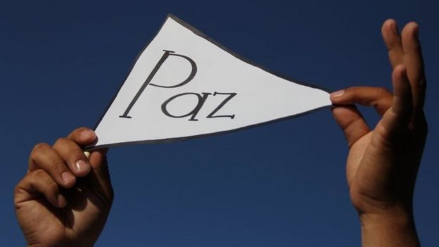 Una persona sostiene un cartel con la palabra "Paz"