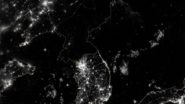 ஒளி மின்னும் ஷென்யாங் நகரத்திற்கும், சோலுக்கு இடையில் கருங்குழி இருப்பது போன்று வட கொரியா தோன்றும் படம்