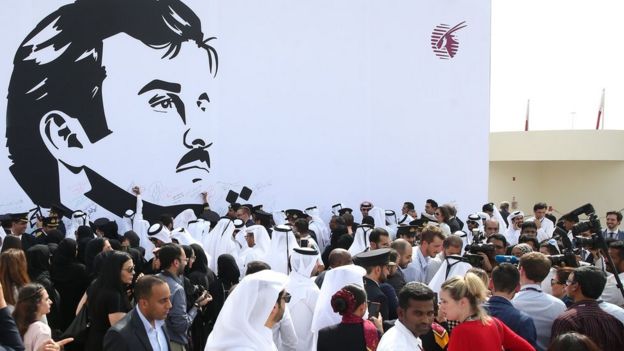 Qatar Airways workers stand in front of a wall bearing a portrait of Qatari Emir Sheikh Tamim bin Hamad Al Thani in support of the country and its leader in Doha. 13 July 2017