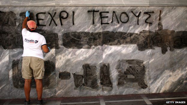 Man scrubs anti-austerity graffiti from wall in Greece