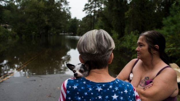 Residents look at a street in a neighbourhood flooded from heavy rains after Storm Florence