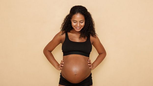 Mulher grávida olhando para a barriga