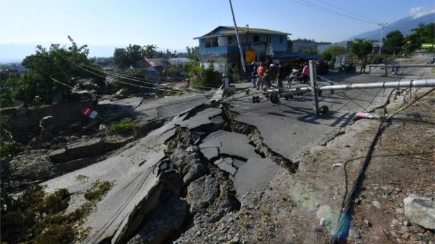 Workers assess a badly cracked road in Palu