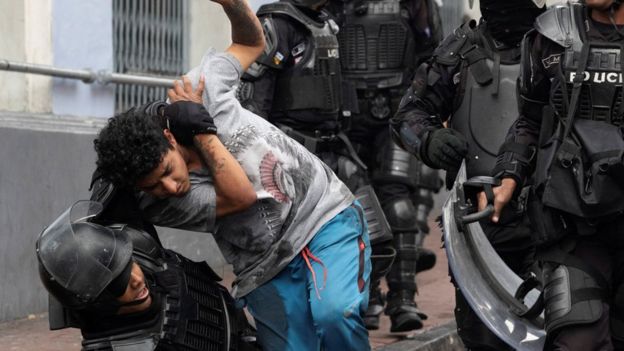 Un chico es agarrado por la policía antidisturbios.