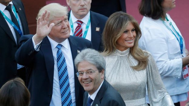 Donald Trump waves as he stands in Sicily next ot his wife Melania