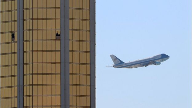 Air Force One passes to the right of the gold-coloured windows of the Mandalay hotel, two of which are shattered from the gunfire during the attack