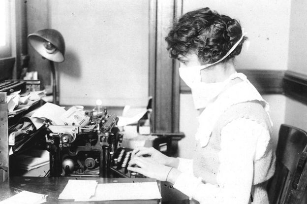 Mujer escribiendo a máquina usando una máscara en 1918.