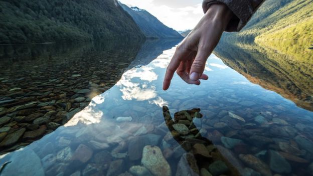 Dedo prester a tocar a água em um lago