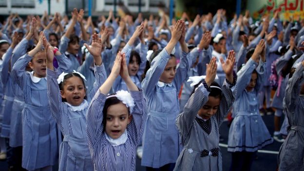 Palestinian school girls raise their hands during a morning exercise at a Unrwa-run school, in Gaza City, on 29 August 2018