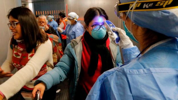 Mujer a la que le ponen un termómetro en el aeropuerto