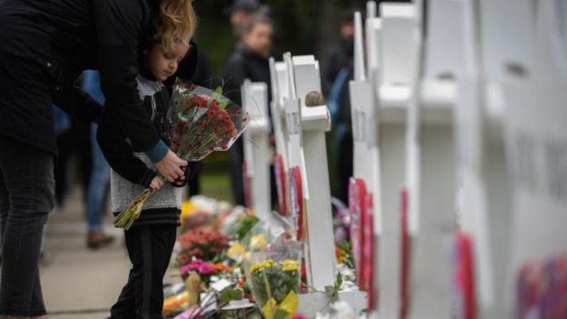 NiÃ±o colocando flores en memorial de muertos por tiroteo