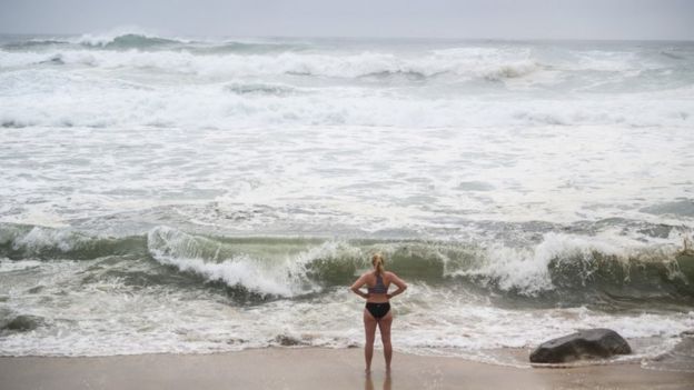 A woman stands by rough sea in Bronte Beach, Sydney (10 Feb 2020)