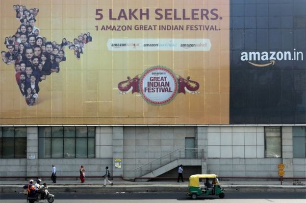 People move past a hoarding of Amazon India outside a metro rail station in New Delhi, India, October 23, 2019