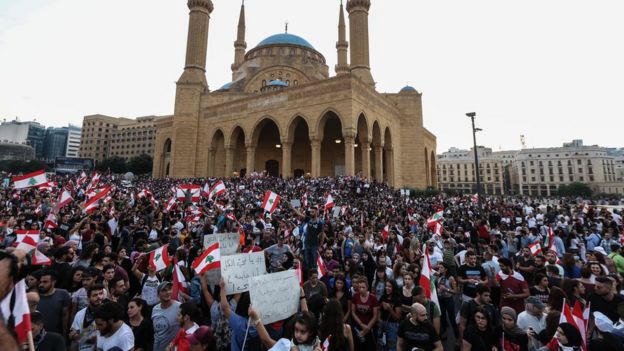 Protesters wave Lebanese flags and shout anti-government slogans in front the government palace in downtown Beirut, Lebanon (19 October 2019)