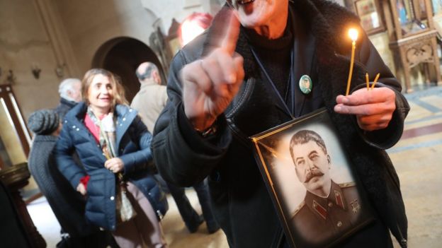 Мужчина со свечкой и портретом Сталина
