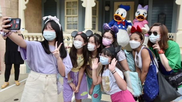 People wearing face masks visit Hong Kong Disneyland on the first day of the reopening.