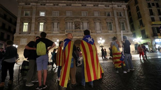 People wrapped with Estaladas (Catalan separatist flags) stand at Sant Jaume square before listening an statement of Catalan President Carles Puigdemont in Barcelona (October 4, 2017)