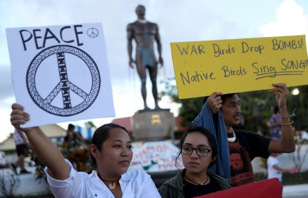 Protesters hold signs during a People for Peace Rally at the Chief Quipuha Statue on 14 August 2017 in Hagatna, Guam.