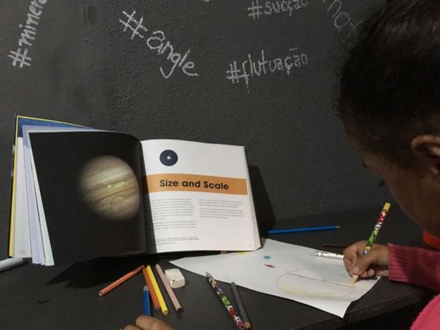 Criança desenhando um planeta, em atividade realizada pelo Project Favela