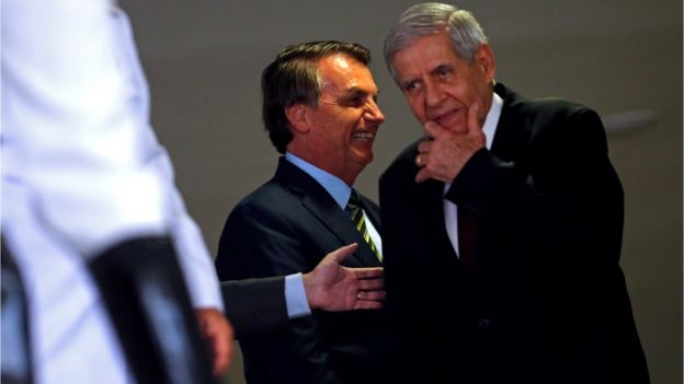Jair Bolsonaro e Augusto Heleno conversam próximos em ambiente interno