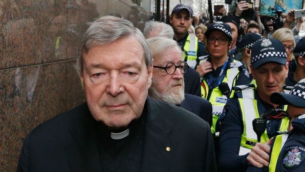 George Pell tailed by his lawyer and a police escort at a court appearance in Melbourne in May 2018