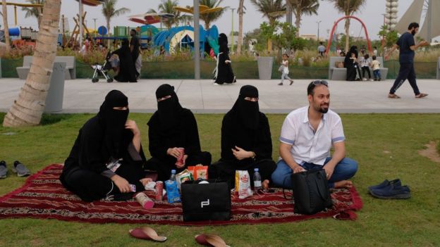 Tres mujeres completamente cubiertas de negro en Arabia Saudita, acompaÃ±adas de un hombre.