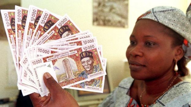 A woman displays several 10,000 CFA